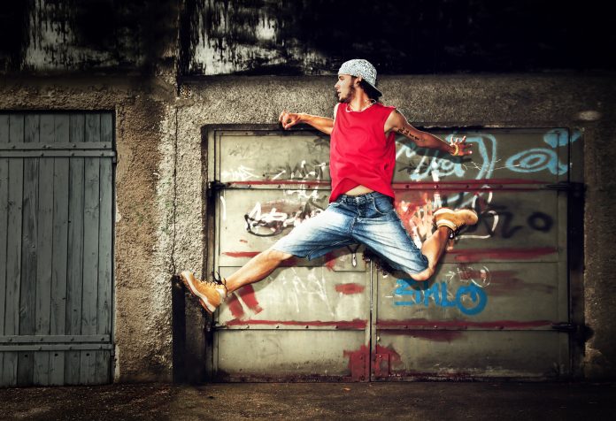 Young man performing a dynamic jump in front of a graffiti wall, symbolizing the energy and creativity involved in starting a YouTube channel