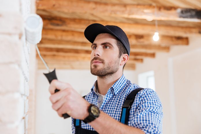 A handyman painting a wall with precision, symbolizing the dedication and skill needed to run a successful handyman business