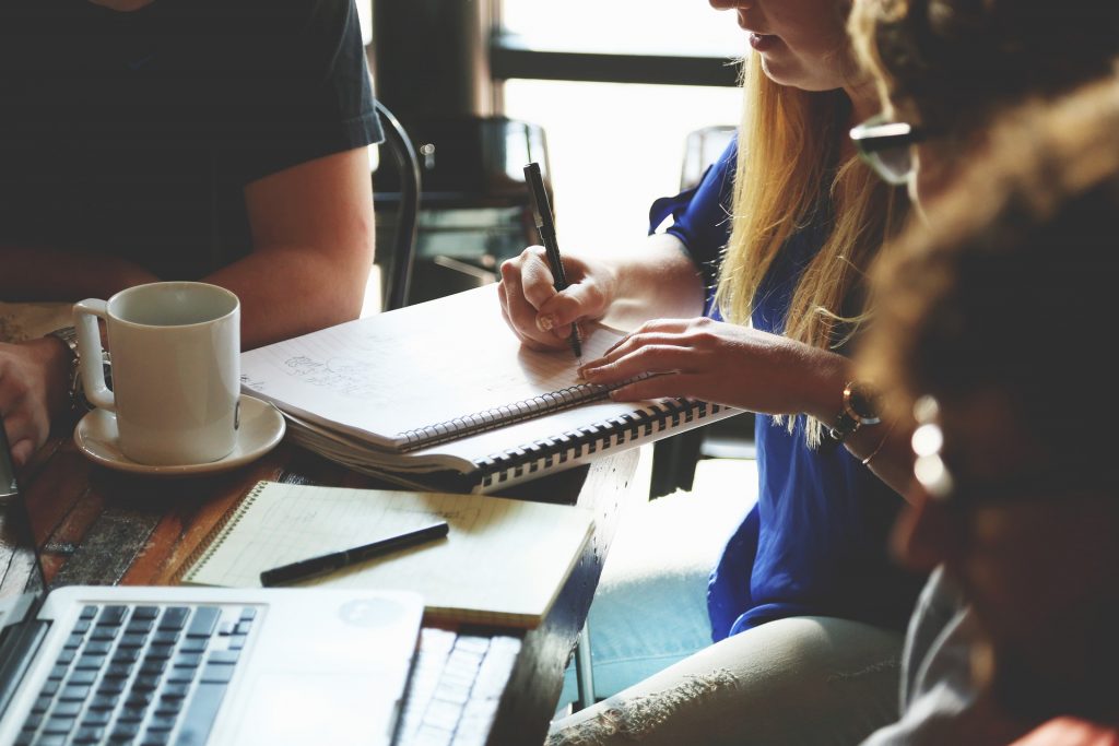 Group of people brainstorming small business ideas at a table with notebooks and laptops