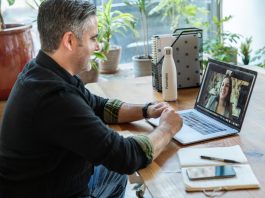 A cozy and organised home office setup with a laptop, notebook, and a bottle of water - a typical virtual assistant's workspace.