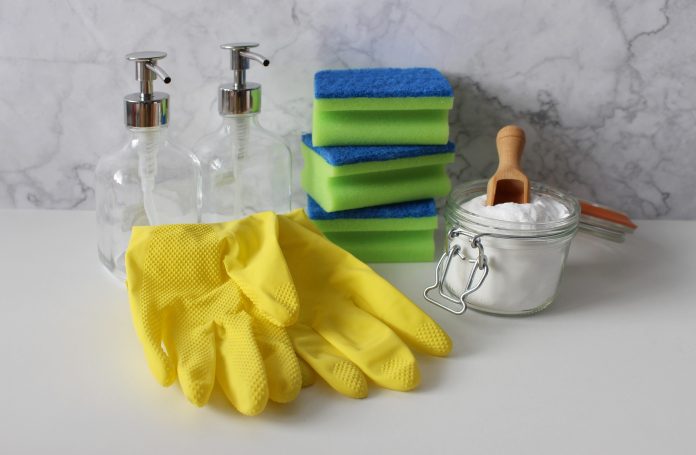 House cleaning supplies including gloves, sponges, and cleaning solutions neatly arranged on a countertop