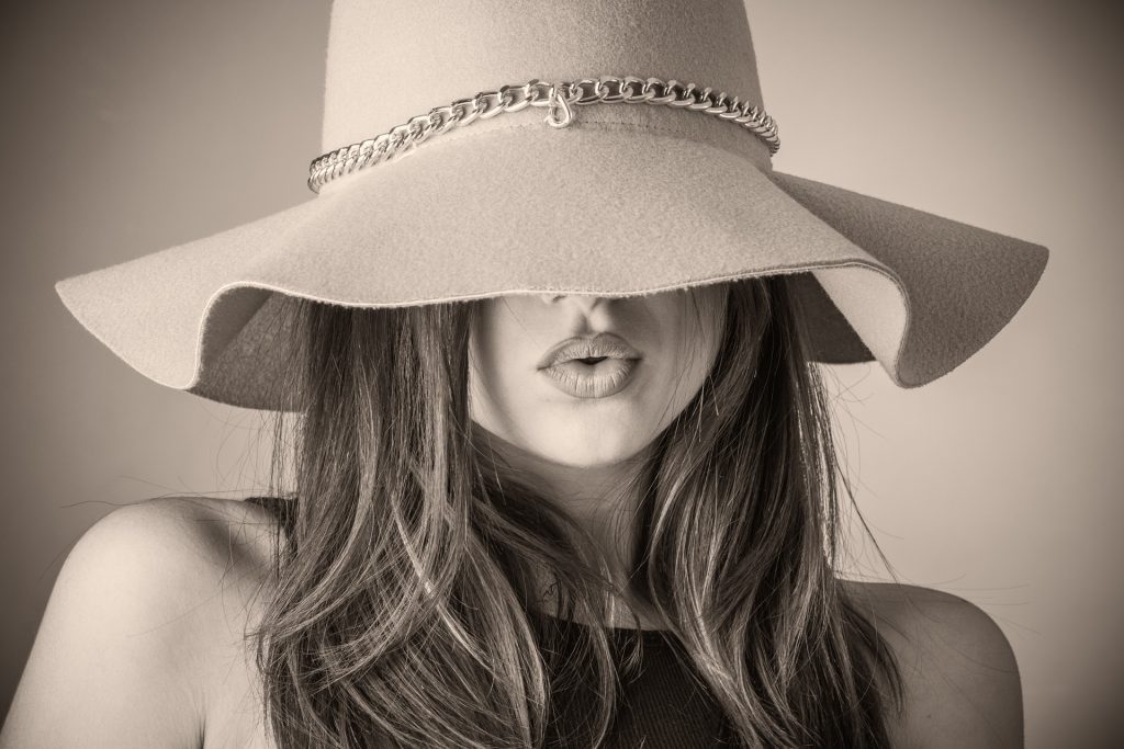 A stylish woman with her face partially hidden by a large hat, representing the creative flair of a professional stylist