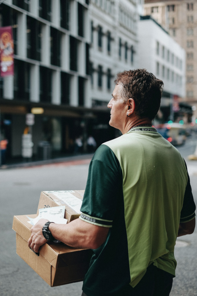 Delivery driver carrying packages through a city street, representing the logistics of urban deliveries