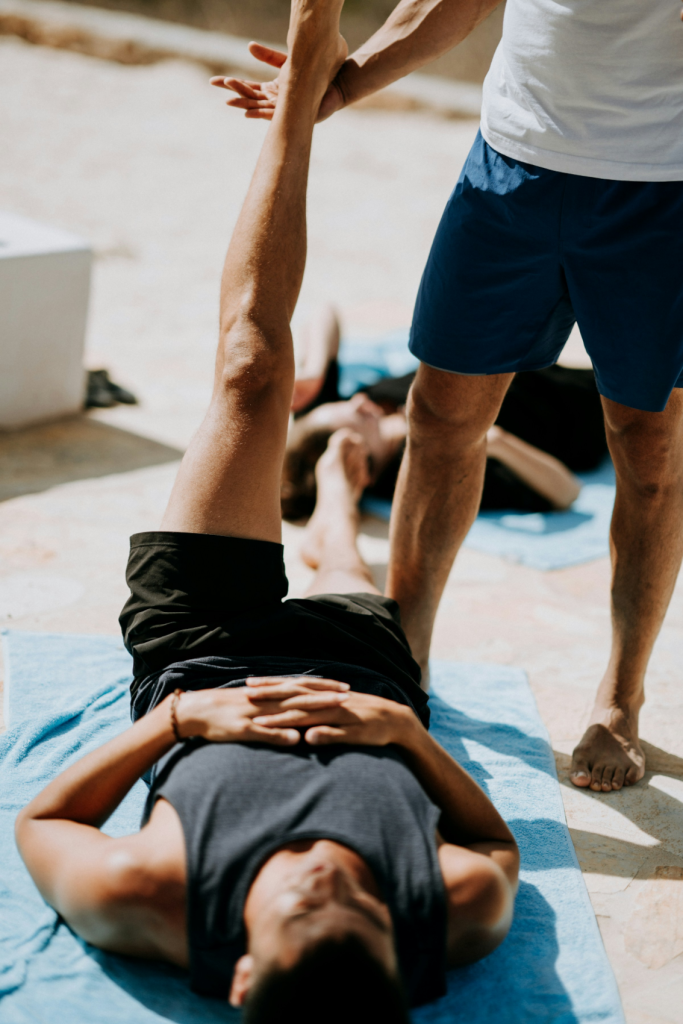 Personal trainer assisting a client with leg stretches during an outdoor fitness session