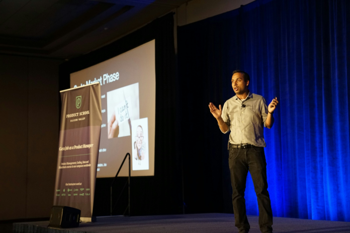 Man delivering a presentation on stage with visuals, demonstrating effective communication techniques